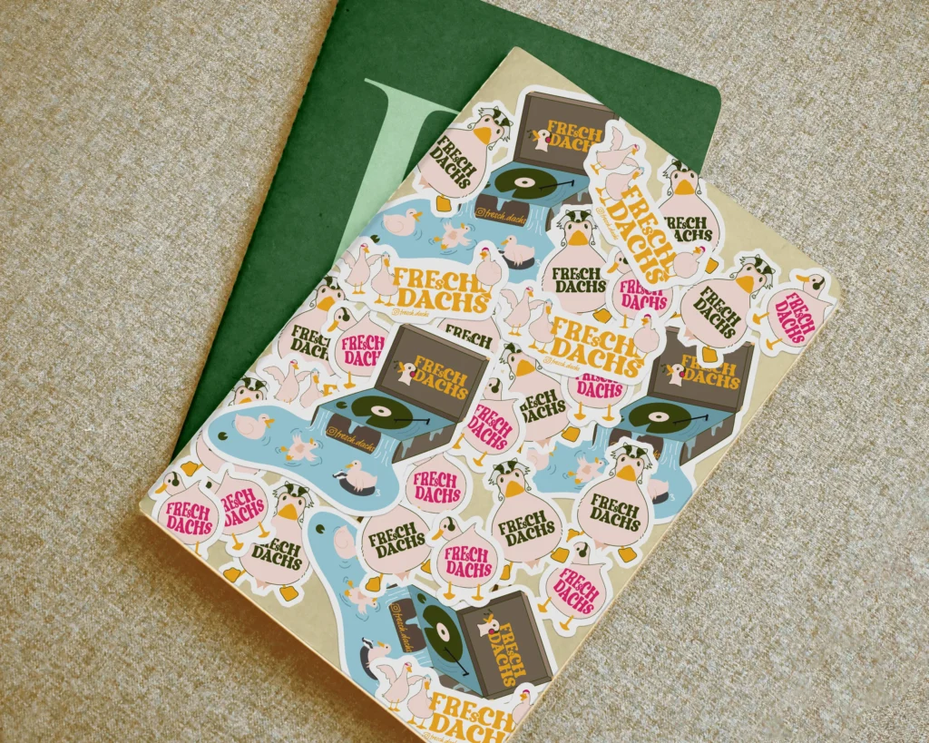 Bunte FreshDachs-Sticker mit illustrierten Enten und Plattenspielern auf einem Notizbuch.