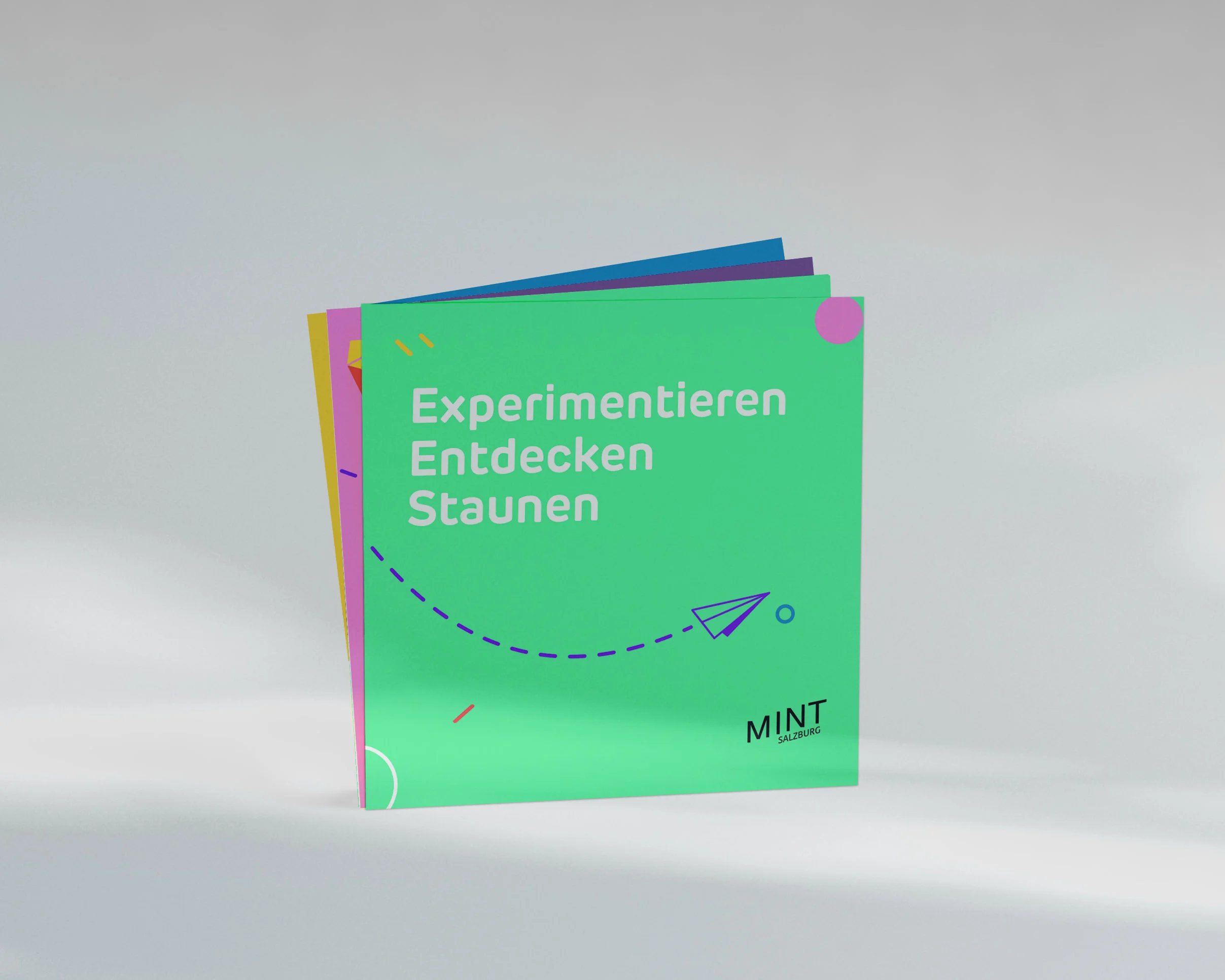 Türkiser Folder von MINT Salzburg mit dem Schriftzug „Experimentieren, Entdecken, Staunen“ und einer Papierflieger-Illustration.